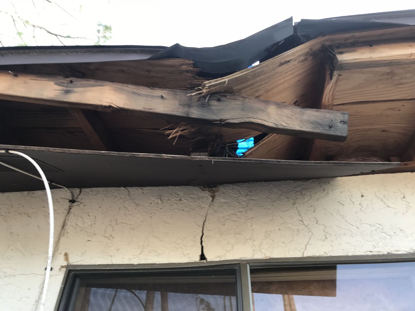 Storm damage to roof eave and stucco wall